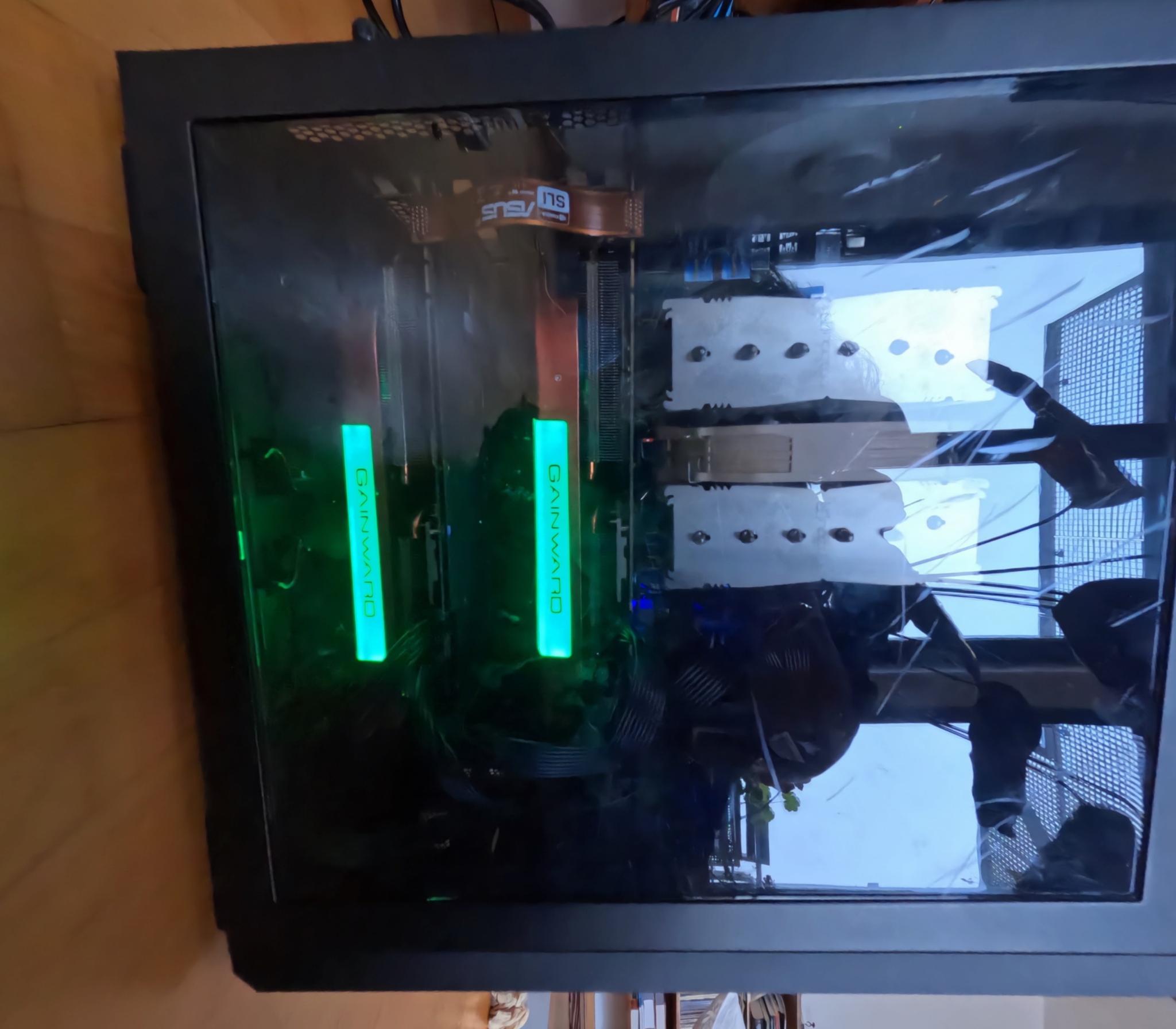 A photo of my older machine, with two green lit up GPUs. You can see it is much larger than the newer one.